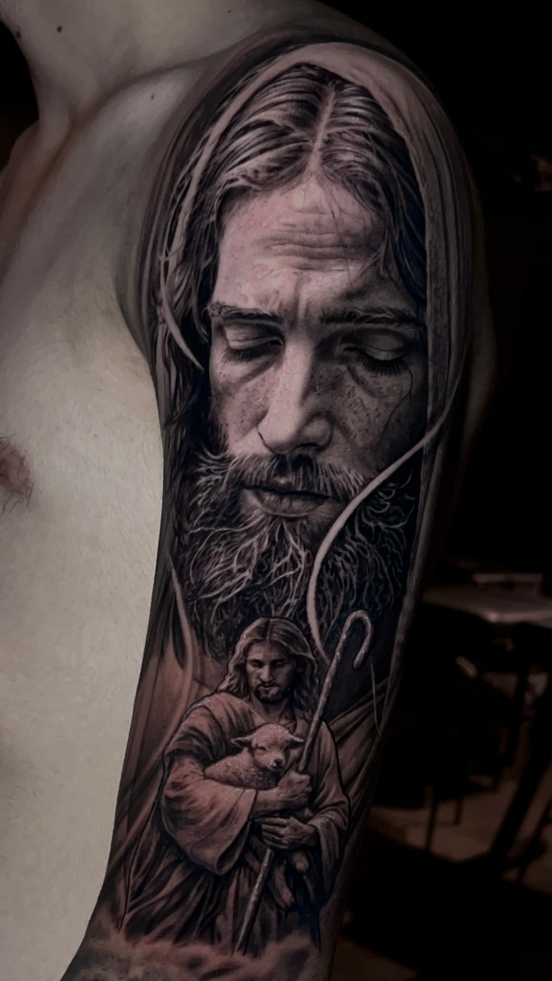 Tatuagem de Jesus com pastor e cordeiro em preto e cinza